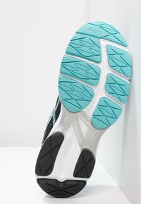 Suola di scarpa sportiva nera con una intersuola bianca testurizzata e dettagli turchesi. Presenta un motivo a zigzag per una migliore aderenza.