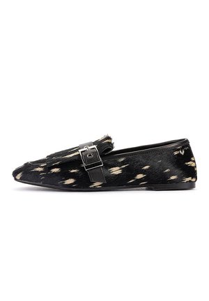 Mocassin plat noir et blanc tacheté avec une boucle argentée sur le dessus, petit talon et bout pointu, présenté de profil sur fond blanc.