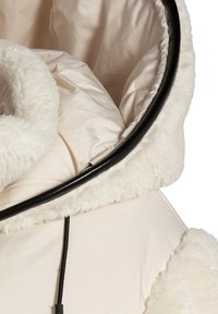 Kremowa kurtka puchowa z miękkim, puszystym kołnierzem i czarnymi metalowymi elementami. Zewnętrzny materiał jest gładki, z ciepłą, teksturowaną podszewką.