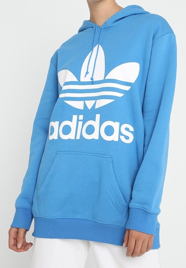 Blå huva sweatshirt i mjukt tyg, med en stor vit Adidas-logotyp och design med tre ränder på framsidan. Framficka ingår.