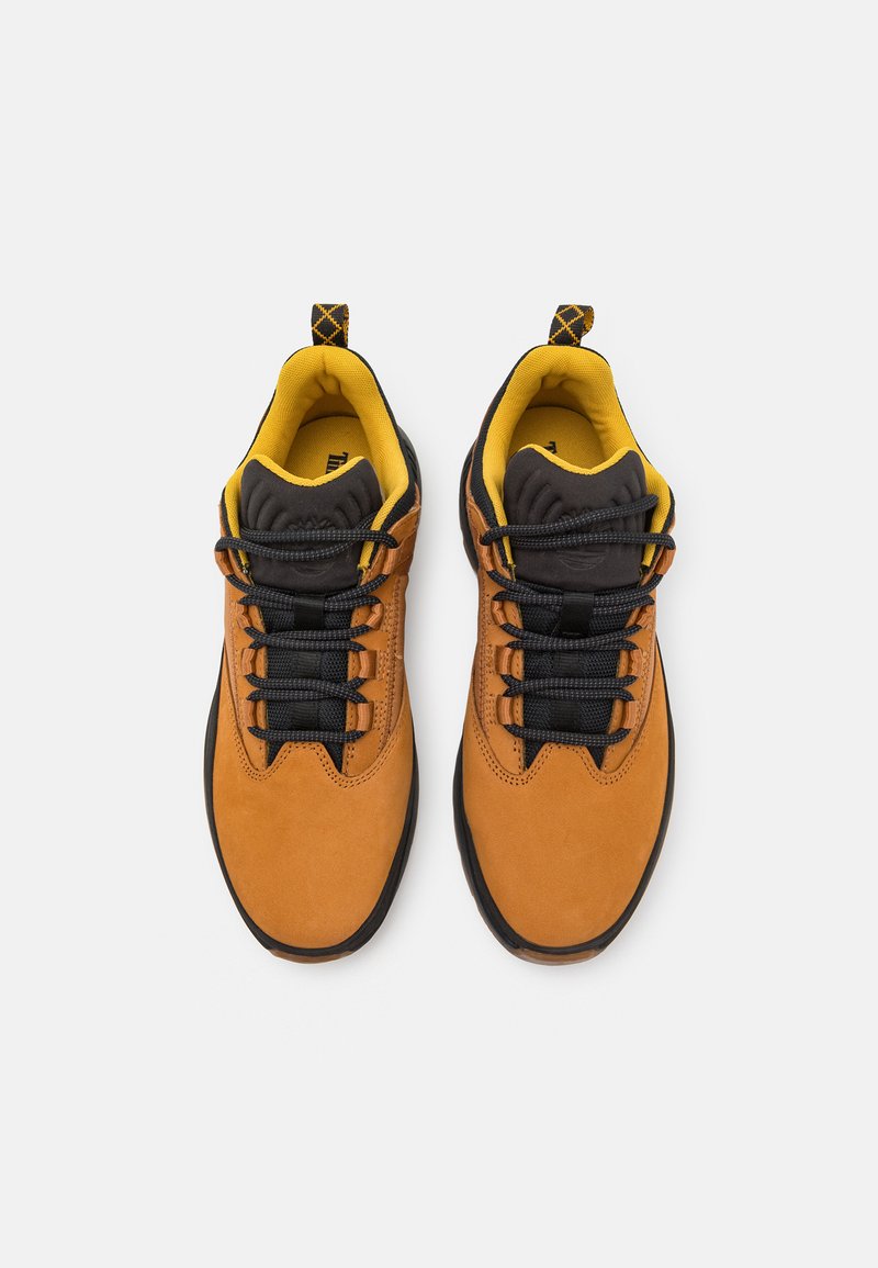 Zamszowe trampki w kolorze tan z czarnymi sznurowadłami i żółtymi akcentami. Okrągły czubek, teksturowana czarna gumowa podeszwa i wyściełany kołnierz dla wygody.