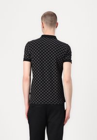 Svart polo skjorte med geometrisk mønster i grått, kort ermer og solid svart krage. Stoffet ser teksturert og tettsittende ut.
