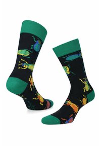 Granatowe skarpetki z zielonymi mankietami, ozdobione kolorowymi ilustracjami chrząszczy w kolorze żółtym, pomarańczowym i niebieskim na teksturowanej tkaninie.