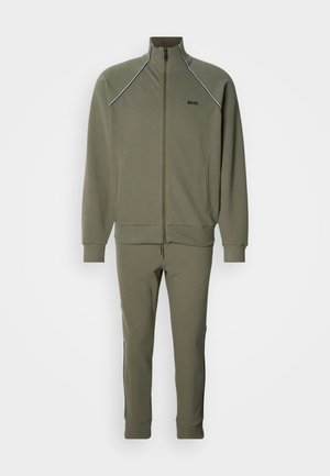 Oliiviroheline dressipluus, millel on lukk ees, soonikkoes mansetid, küljetaskud ning sobivad kitsenevad püksid mustade detailidega.