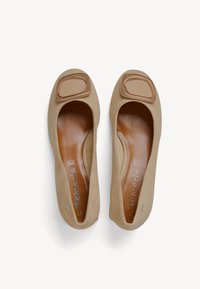 Beige ballet flats made of suede with a smooth leather insole, featuring a square brown accent on the toe and rounded shape.