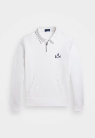 Valge kapuutsita särk, millel on veerandipikkuses tõmblukk, eesmine tasku ja tumesinine luksulogo. Valmistatud pehmest kangast, klassikalise kraega.