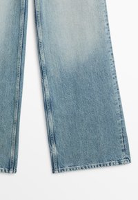 Lyseblå denimjeans med vid benform, synlige syninger langs sømmene og en let falmet vask.