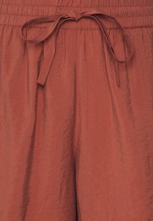 Pantalon ample en tissu couleur rouille avec ceinture élastiquée froncée et cordon noué au centre devant.