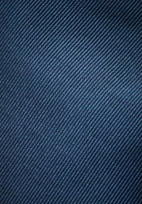 Marinblått tyg med en fin diagonalt ribbad textur. Materialet verkar slätt med en lätt lyster och ett jämnt mönster genom hela tyget.