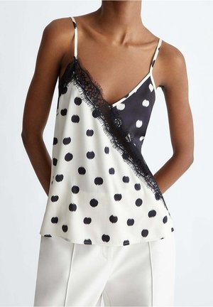 Camisole en satin noir et blanc avec une fente diagonale ornée de grands pois, bordure en dentelle le long de l'encolure et fines bretelles réglables.