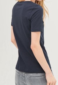 T-shirt en coton bleu marine à manches courtes, décolleté rond et coupe ajustée. Il présente une texture lisse et un ourlet subtil.