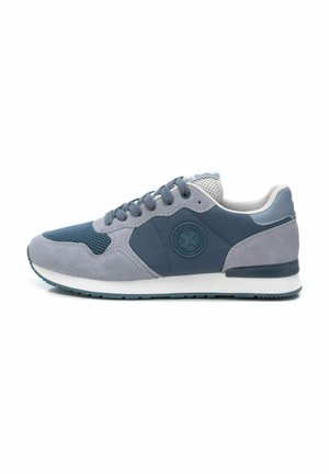 Zapatilla de hombre que presenta una mezcla de ante gris y malla con un acento azul. Punta redondeada, suela en contraste y logo circular decorativo en el lateral.