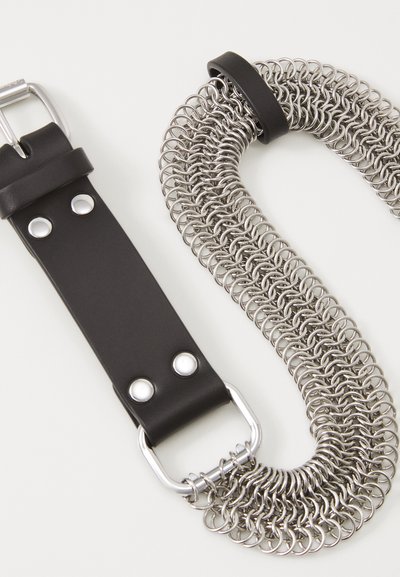 Schwarzes Lederarmband mit silberfarbener Schnalle, kombiniert mit einer Kette aus miteinander verbundenen Metallringen. Glatte Textur, industrielles Design.