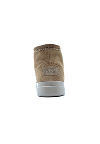 Botte de cheville en suede marron avec un bout arrondi, un dessus piqué et une semelle en caoutchouc gris. Présente un petit logo cousu à l'arrière.