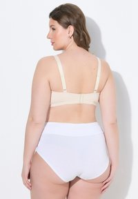 Béžová podprsenka s nastavitelnými ramínky a zapínáním na háček, v kombinaci s bílými kalhotkami s vysokým pasem vyrobenými z hladkého, elastického materiálu.