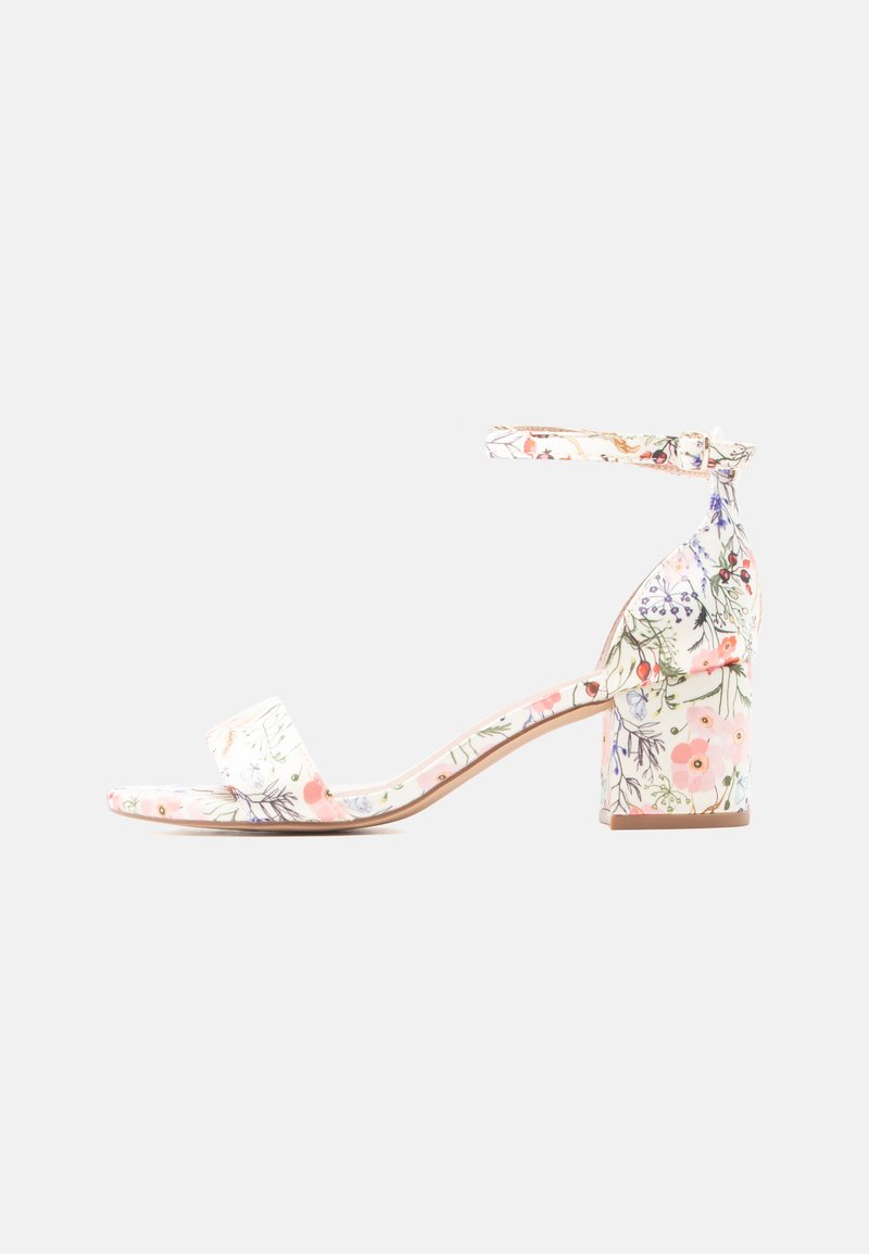 Sandale à talon bloc blanc avec motif floral rose et violet, bout ouvert, bride à la cheville, et fermeture à boucle.