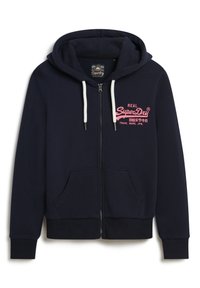 Felpa con zip di colore navy realizzata in cotone, con un logo frontale rosa. Presenta un cappuccio con cordino e due tasche frontali. Orlo e polsini a coste.