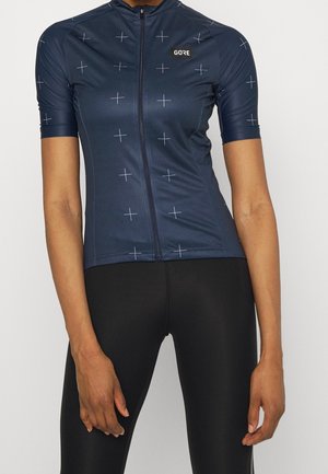 Maillot de cyclisme bleu marine à manches courtes avec motif de croix blanches et fermeture éclair devant, assorti à un cuissard noir.