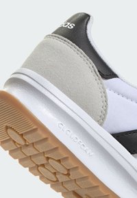 Biele a sivé tenisky z nubuku a textilu, s čiernymi akcentami a štruktúrovanou gumovou podrážkou, označené ako "CLOUDFOAM."