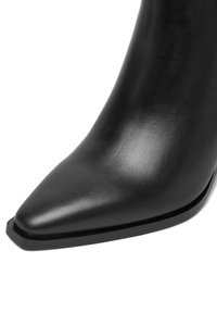 Bota de cuero negro con punta puntiaguda y suela de borde cuadrado, textura suave y un ligero brillo.