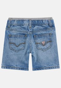 Pantalones cortos de mezclilla azul claro con una cinturilla elástica gris, que cuentan con dos bolsillos traseros y un parche con el logo en el bolsillo derecho.