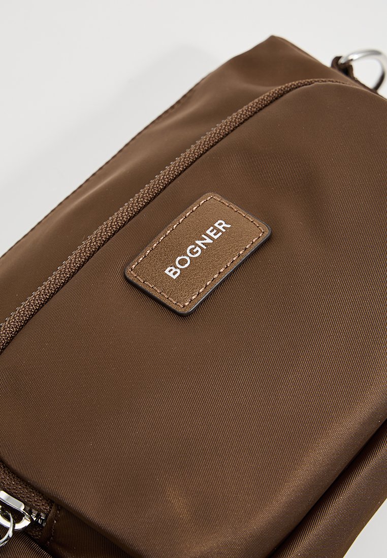 Borsa in tessuto marrone con una superficie liscia, dotata di un compartimento con cerniera e di un'etichetta in pelle rettangolare impresso con "BOGNER."
