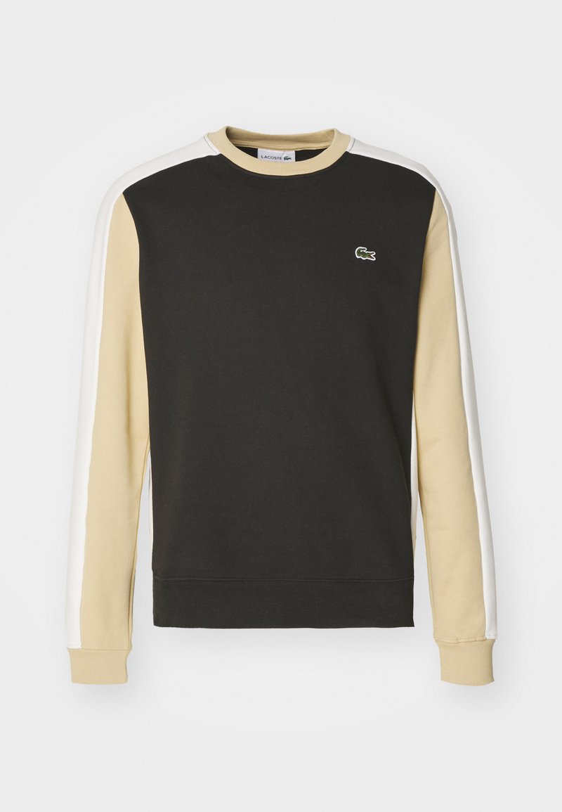 Sweatshirt noir avec des manches beige et blanches. Il présente un col rond, des poignets côtelés et un petit logo de crocodile vert sur la poitrine.