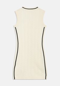 Μάλλινο φόρεμα χωρίς μανίκια σε κρεμ χρώμα με σχέδιο καλωδίων, εφαρμοστή γραμμή και αντίθετες μαύρες ρίγες στο πλάι κατά μήκος των ραφών.