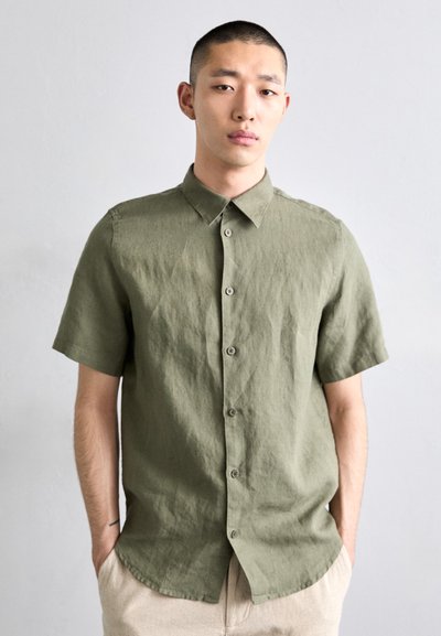 Chemise à manches courtes olive en tissu texturé, avec un col pointu et cinq boutons à l'avant.