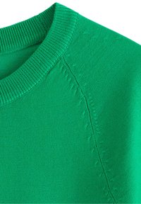 Grøn sweater med ribbet halsudskæring og glat tekstur, med subtile stikninger langs skuldersømmen.