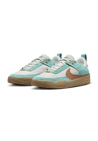 Nike tenisky s ľahkým modrým semišovým zvrškom, bielymi sieťovinovými vložkami, hnedými akcentmi a textúrovanou gumovou podrážkou. Dizajn s šnúrkami.
