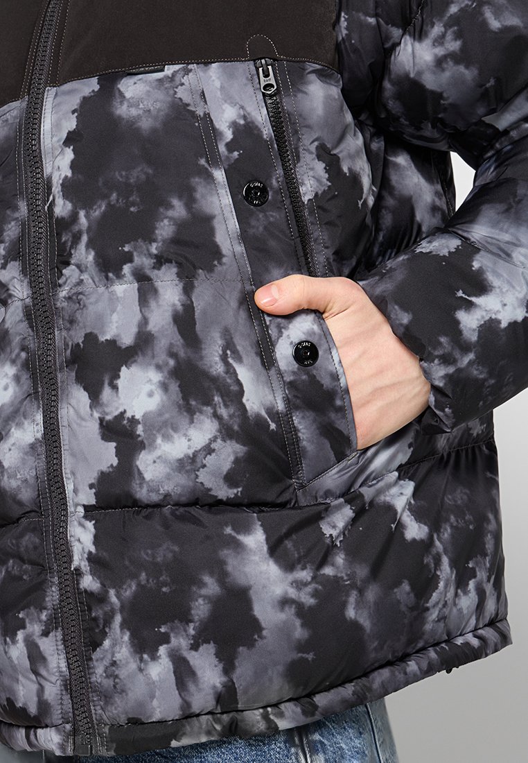 Czarna kurtka puchowa z szarym wzorem tie-dye, wyposażona w zamek błyskawiczny, kieszenie na guziki oraz miękką, pikowaną teksturę.