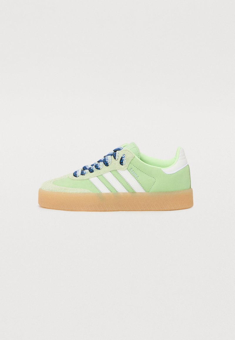 Grønne ruskinds sneakers med hvide striber, gummisål og blå mønstrede snørebånd. Har tekstureret tå og polstret krave for komfort.