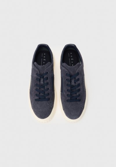 Pair of navy blue suede sneakers with white rubber soles and black laces, viewed from above on a white background.