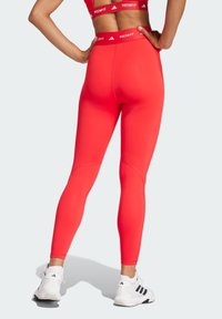 Røde højtaljede leggings lavet af strækbart stof, med et sømløst design og en kontrasterende mærkebånd.