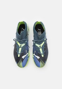 Scarpe sportive nere e blu con parte superiore in rete, accenti verde neon e design testurizzato. Presentano un logo prominente e lacci.