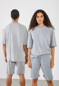 Sivý zladený set pozostávajúci z vo�ľného trička a šortiek. Mäkká, textúrovaná tkanina, krátke rukávy a elastický pás. Minimalistický dizajn.
