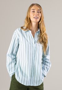 Light blue button-up shirt with green vertical stripes; features a pointed collar and long sleeves with buttoned cuffs. Smooth cotton material.