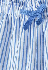 Tissu rayé bleu clair et blanc avec une taille froncée. Comprend un cordon de serrage bleu noué en nœud. La texture semble lisse.