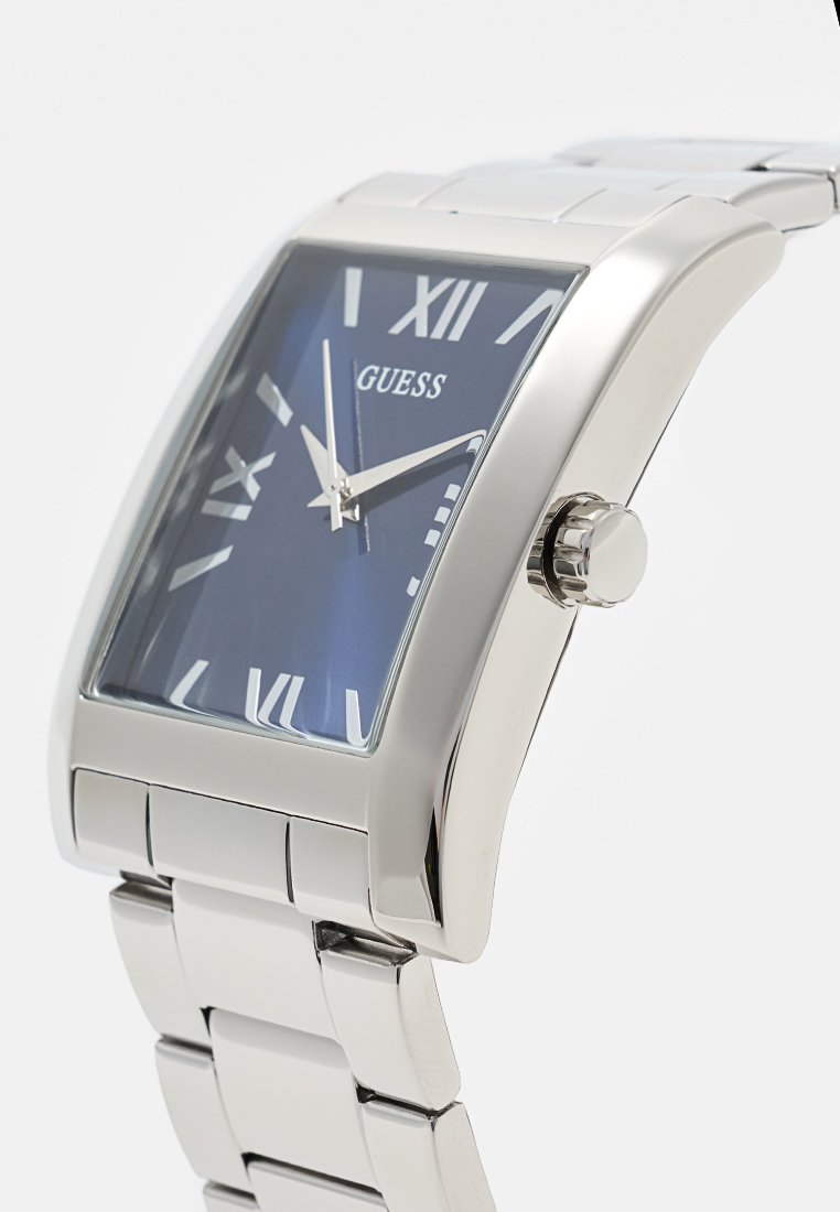 Reloj de acero inoxidable plateado con una esfera rectangular azul. Cuenta con números romanos blancos, una ventana para la fecha y un diseño de pulsera texturizada.