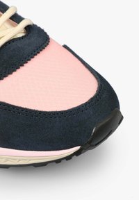 Gros plan sur l’avant d’une basket rose et bleu marine avec tissu texturé, empiècement en daim, lacets crème et détail de semelle en caoutchouc noir.