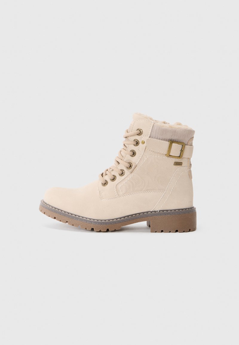 Botas de tobillo beige con un diseño texturizado, forro de piel sintética, ojales de metal y suela de goma marrón. Presentan un detalle de hebilla en el lateral.