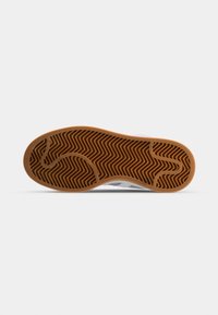 Rubber shoe sole featuring a zigzag tread pattern, light brown color, with a smooth edge and slight curvature for flexibility.