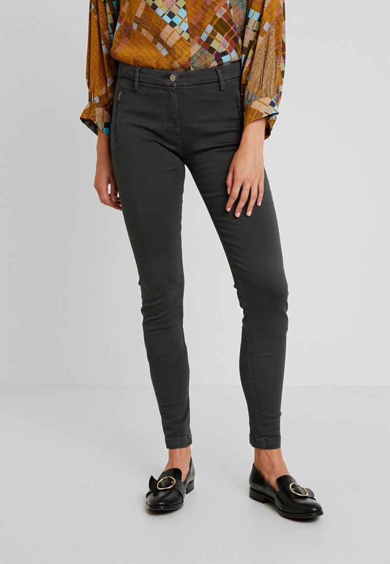 Grå, slim-fit byxor med en mjuk textur, med framfickor och knäppning. Matchas med svarta loafers med ett guld accent.