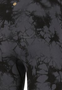 Leggings noirs avec un motif abstrait texturé dans des nuances variées de noir. Présente un petit logo doré près de la taille.