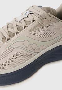 Light beige running shoe with mesh upper, beige laces, brand logo on side, and thick black sole.