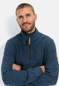 Navy blue knitted pullover with a high collar, quarter zip, and leather zipper pull. Ribbed texture and woven fabric details present.