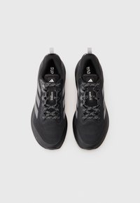 Baskets de sport noires avec une tige texturée, trois rayures grises, des accents réfléchissants et des lacets à motifs ; elles disposent d'un col et d'une languette rembourrés.