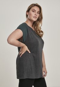 Grijze T-shirt met korte groene mouwen, een relaxte pasvorm en een ronde halslijn. Zachte katoenmix stof met zijzakken.
