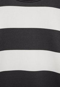 Tela a rayas en blanco y negro con franjas horizontales gruesas. El material parece suave con una textura lisa. Cuello redondo visible.